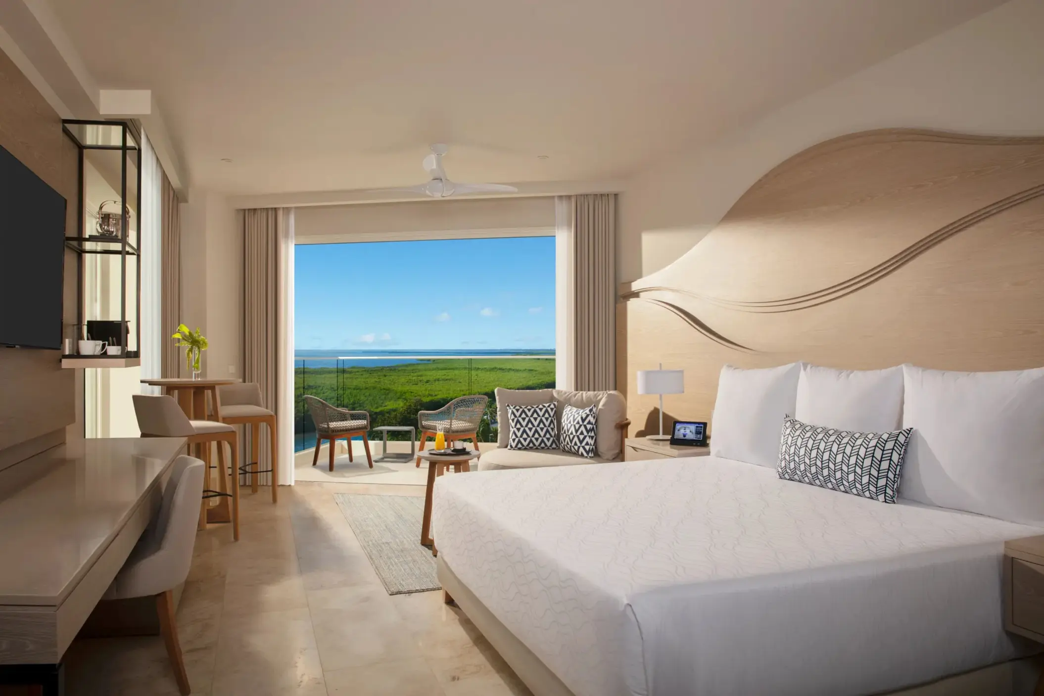 Junior suite with king bed, sitting area, and furnished terrace overlooking the lagoon.