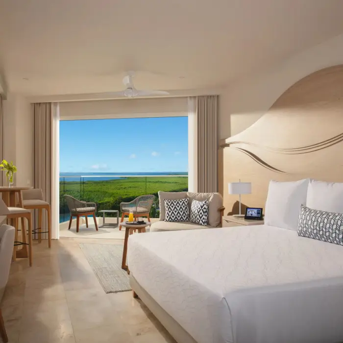 Junior suite with king bed, sitting area, and furnished terrace overlooking the lagoon.