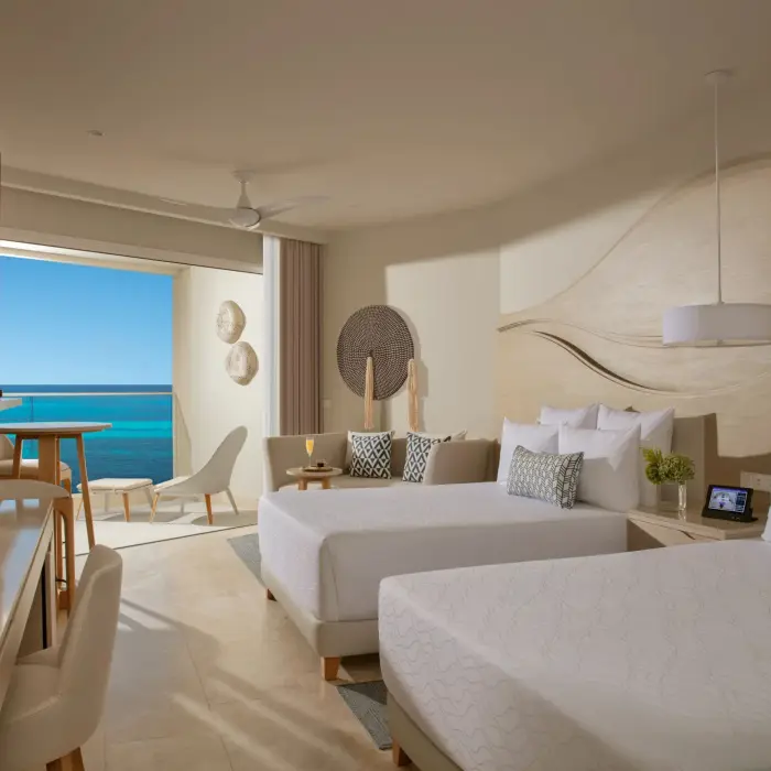 Double-bed room with ocean view balcony, warm lighting, and stylish curved wood wall design.