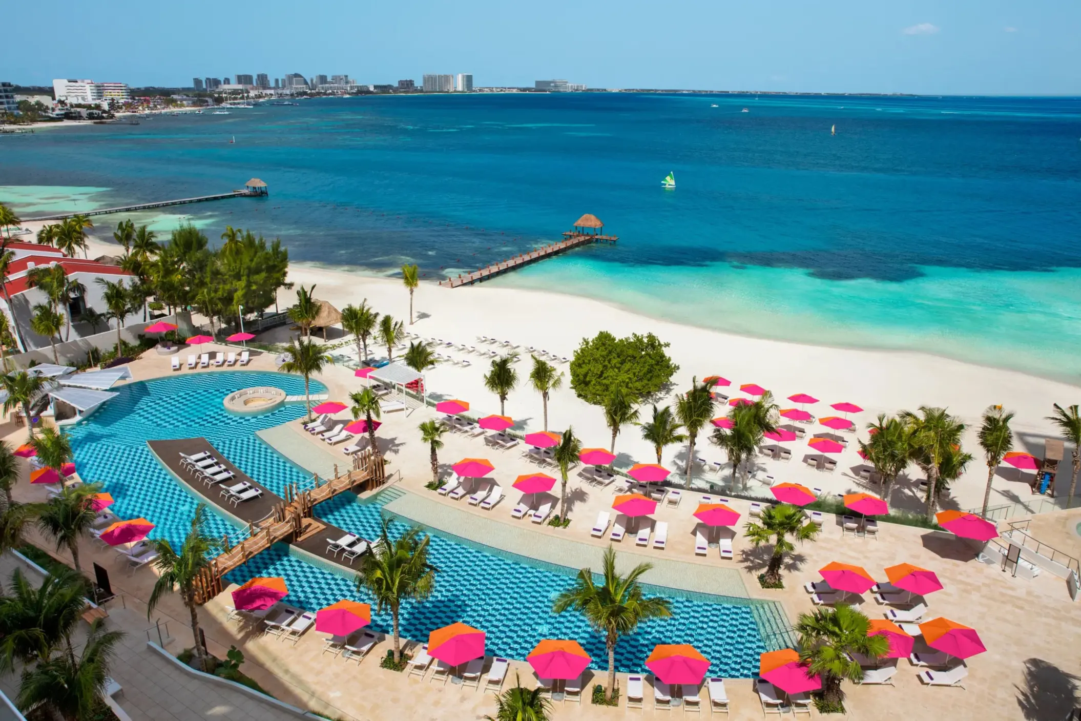 Aerial view of the Energy Pool and beach area with pink umbrellas at Breathless Cancun Soul Resort & Spa.