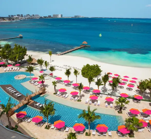 Aerial view of the Energy Pool and beach area with pink umbrellas at Breathless Cancun Soul Resort & Spa.