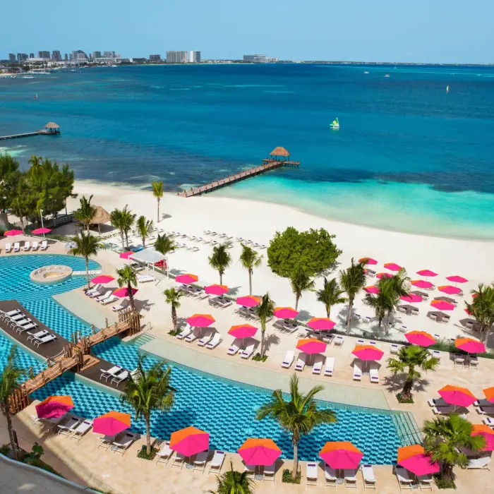 Aerial view of the Energy Pool and beach area with pink umbrellas at Breathless Cancun Soul Resort & Spa.