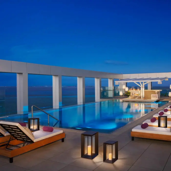 XC rooftop pool glowing at night with lanterns and bar service overlooking the ocean at Breathless Cancun Soul.