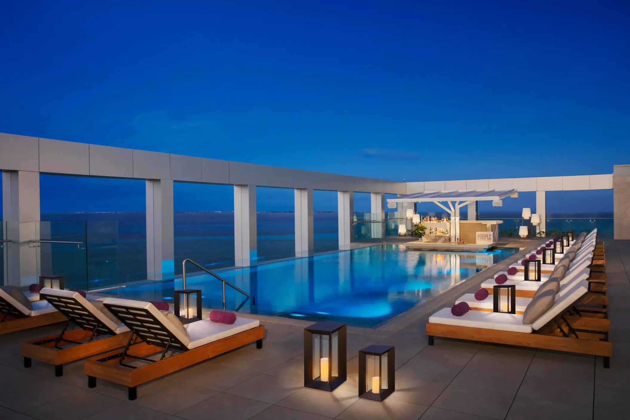 XC rooftop pool glowing at night with lanterns and bar service overlooking the ocean at Breathless Cancun Soul.
