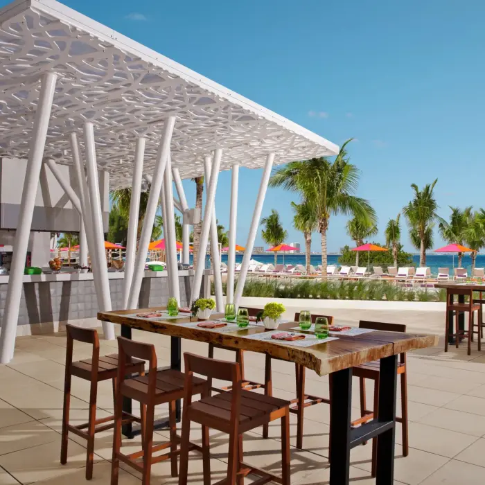 Casual outdoor setup at Barefoot Grill near the pool area with palm trees and colorful umbrellas.