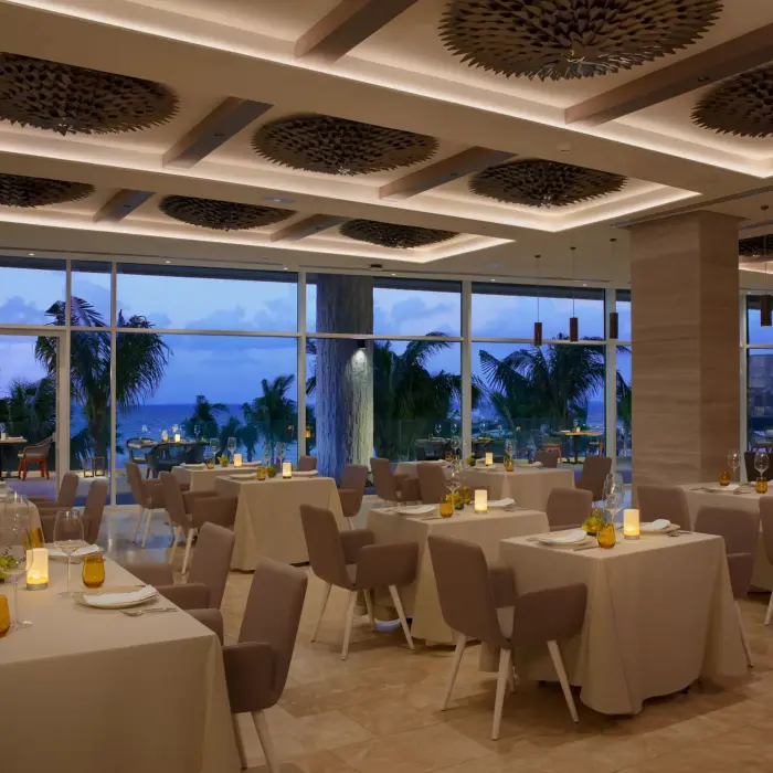 Elegant indoor dining setup at Kibbeh restaurant with ocean views and soft evening lighting.