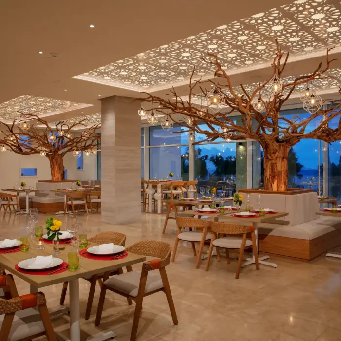Elegant dining area at Picante restaurant featuring wood accents, tree sculptures, and ambient lighting.