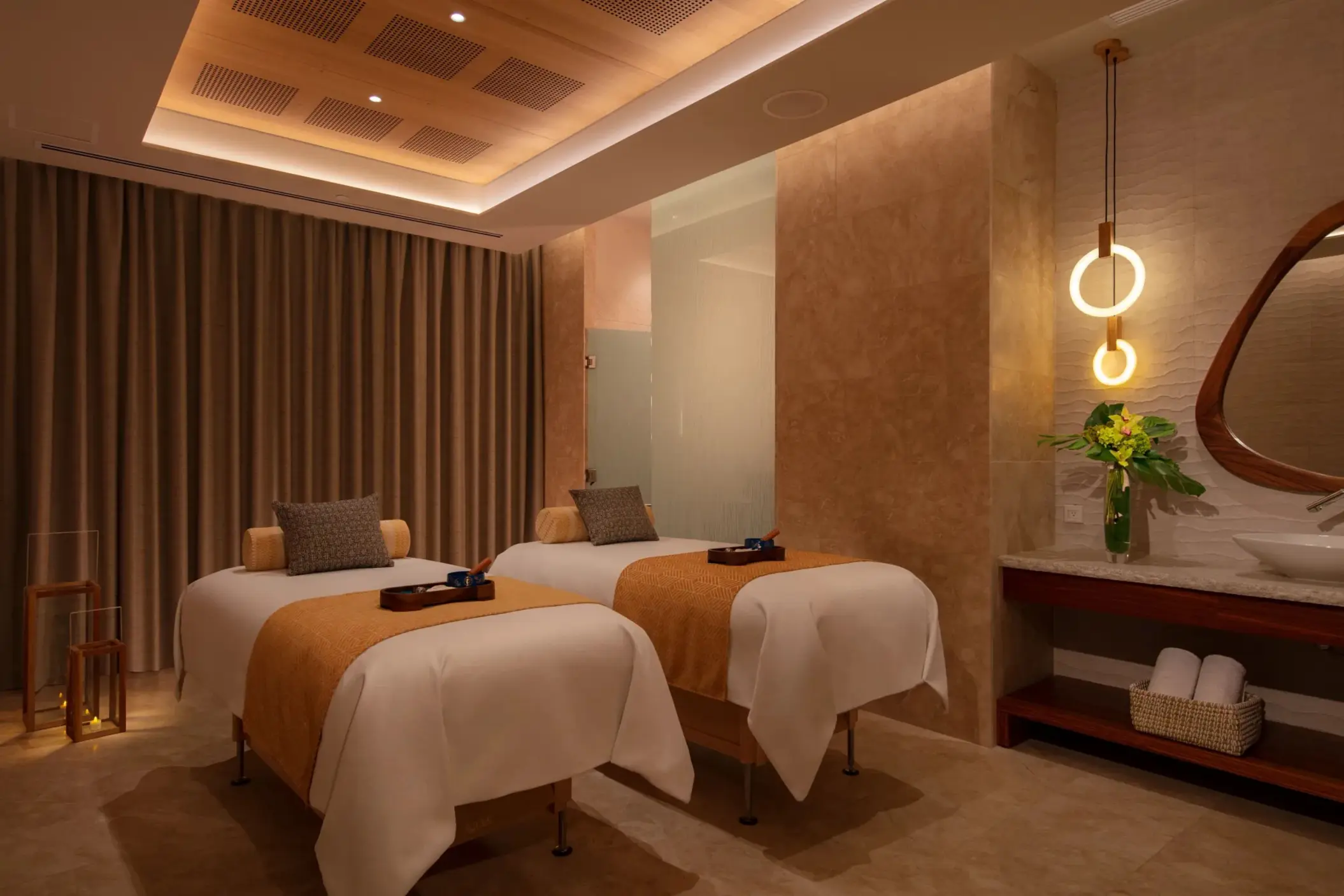 Peaceful treatment room at the spa with two massage beds, warm lighting, and neutral tones.