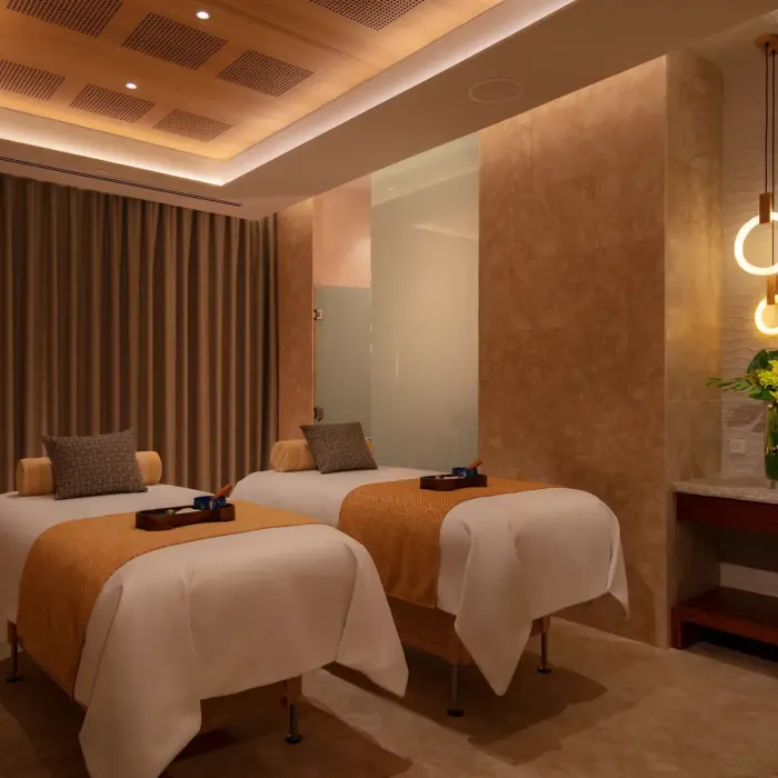 Peaceful treatment room at the spa with two massage beds, warm lighting, and neutral tones.