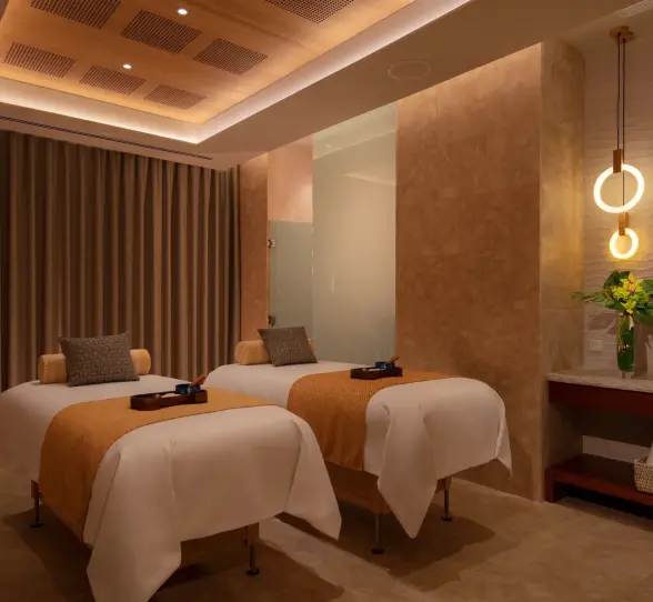 Peaceful treatment room at the spa with two massage beds, warm lighting, and neutral tones.