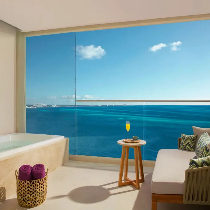 Spacious terrace suite with ocean views, private hot tub, and cozy seating area for relaxing moments.