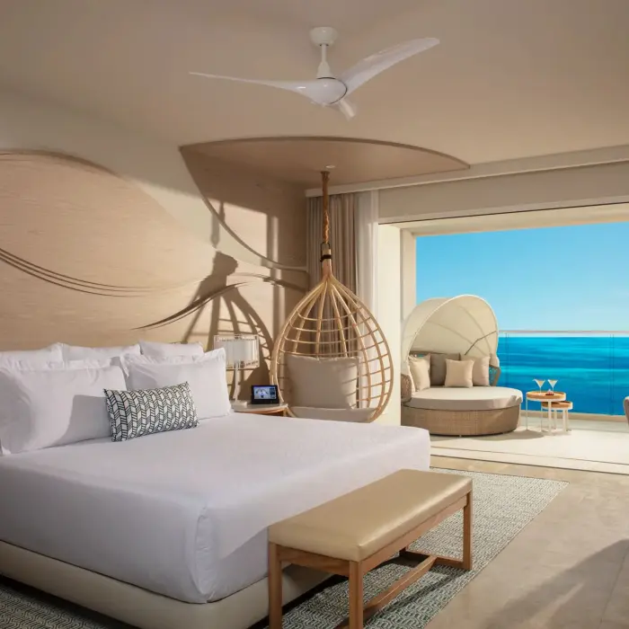 Spacious oceanview suite with king bed, hanging chair, and balcony lounge at Breathless Cancun Soul.