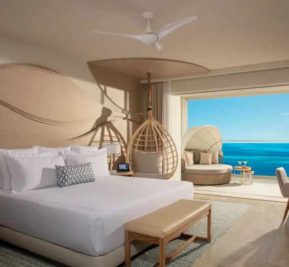 Spacious oceanview suite with king bed, hanging chair, and balcony lounge at Breathless Cancun Soul.