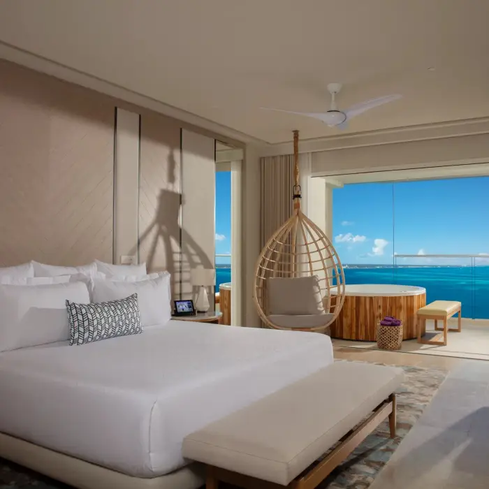Luxurious oceanfront suite with hanging chair, king bed, and private terrace hot tub at Breathless Cancun Soul.