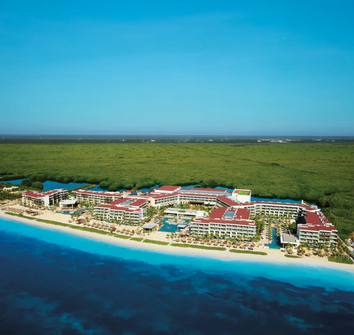 Aerial view of Breathless Riviera Cancun along turquoise coastline and lush green jungle.