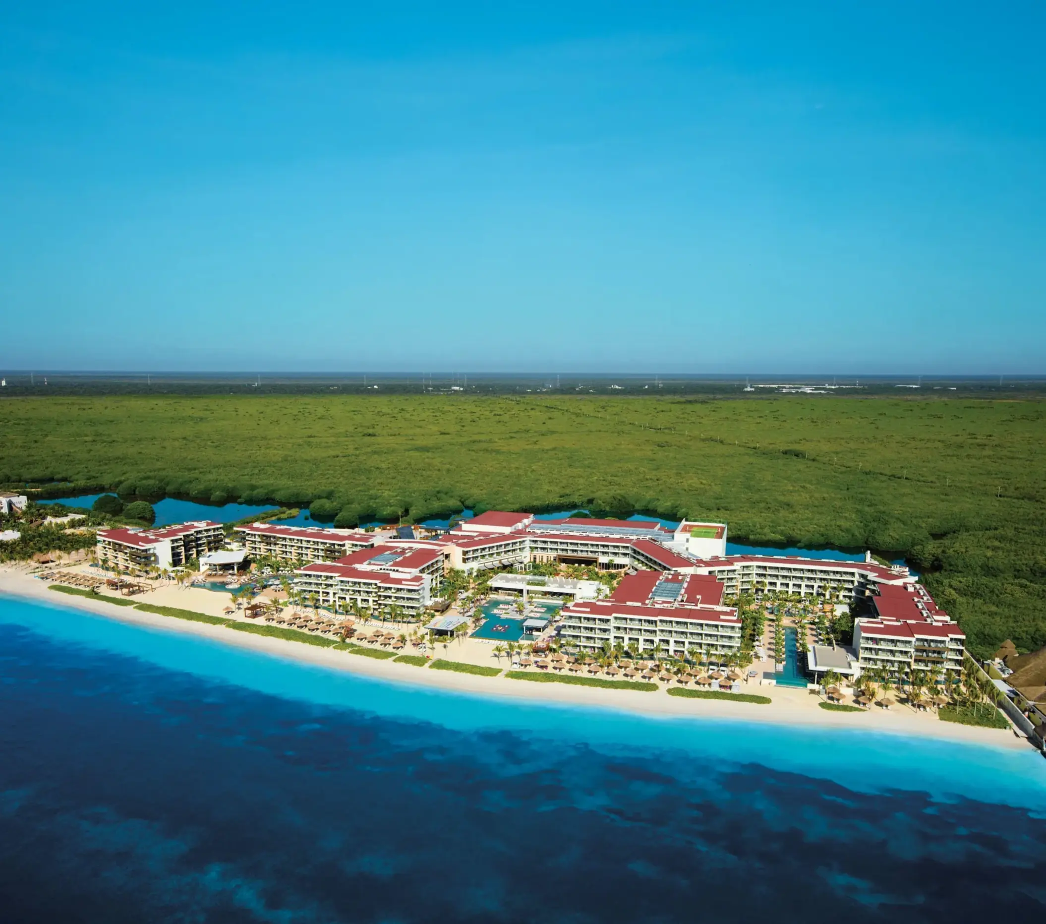 Aerial view of Breathless Riviera Cancun along turquoise coastline and lush green jungle.