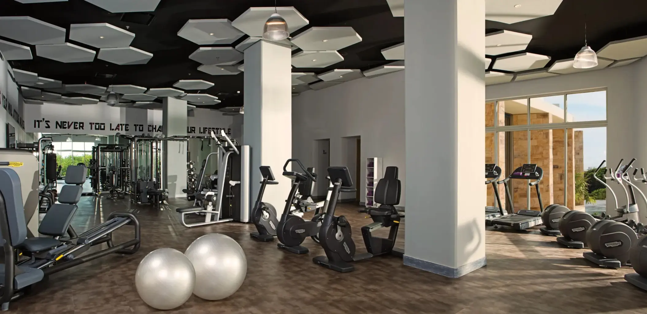 Modern fitness center at Breathless Riviera Cancun with cardio machines, weights, and floor-to-ceiling windows.