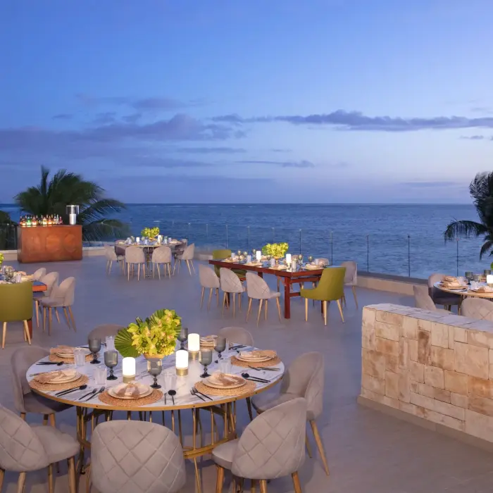 Oceanfront banquet setup on terrace at Breathless Riviera Cancun with elegant tables, candles, and sea views.