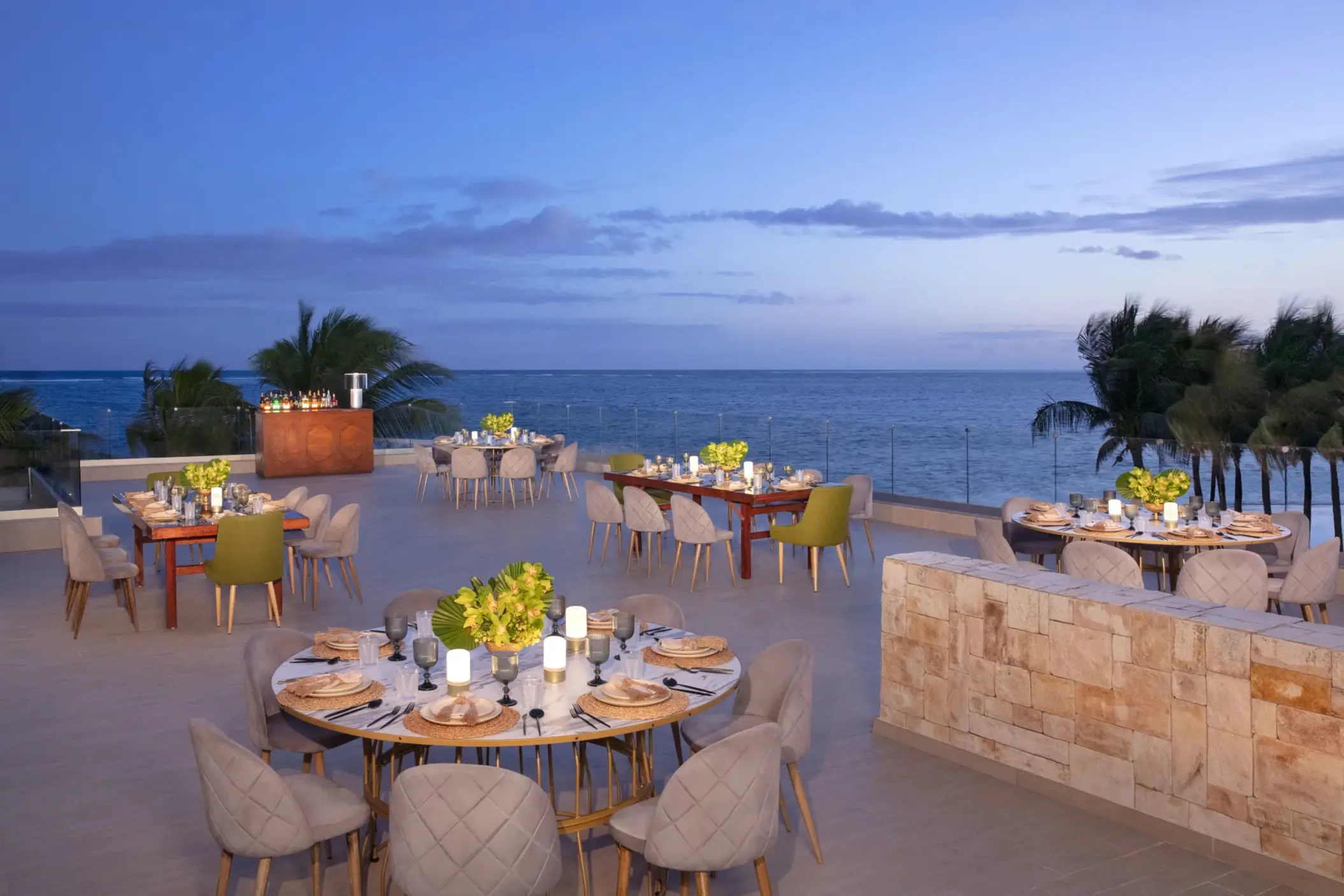 Oceanfront banquet setup on terrace at Breathless Riviera Cancun with elegant tables, candles, and sea views.