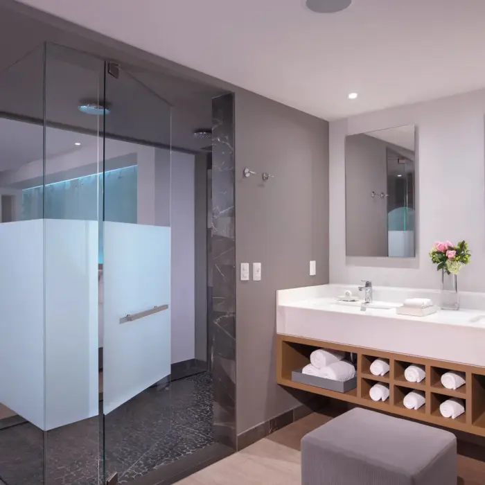 Modern junior suite bathroom with dual vanities, glass shower, and clean design.