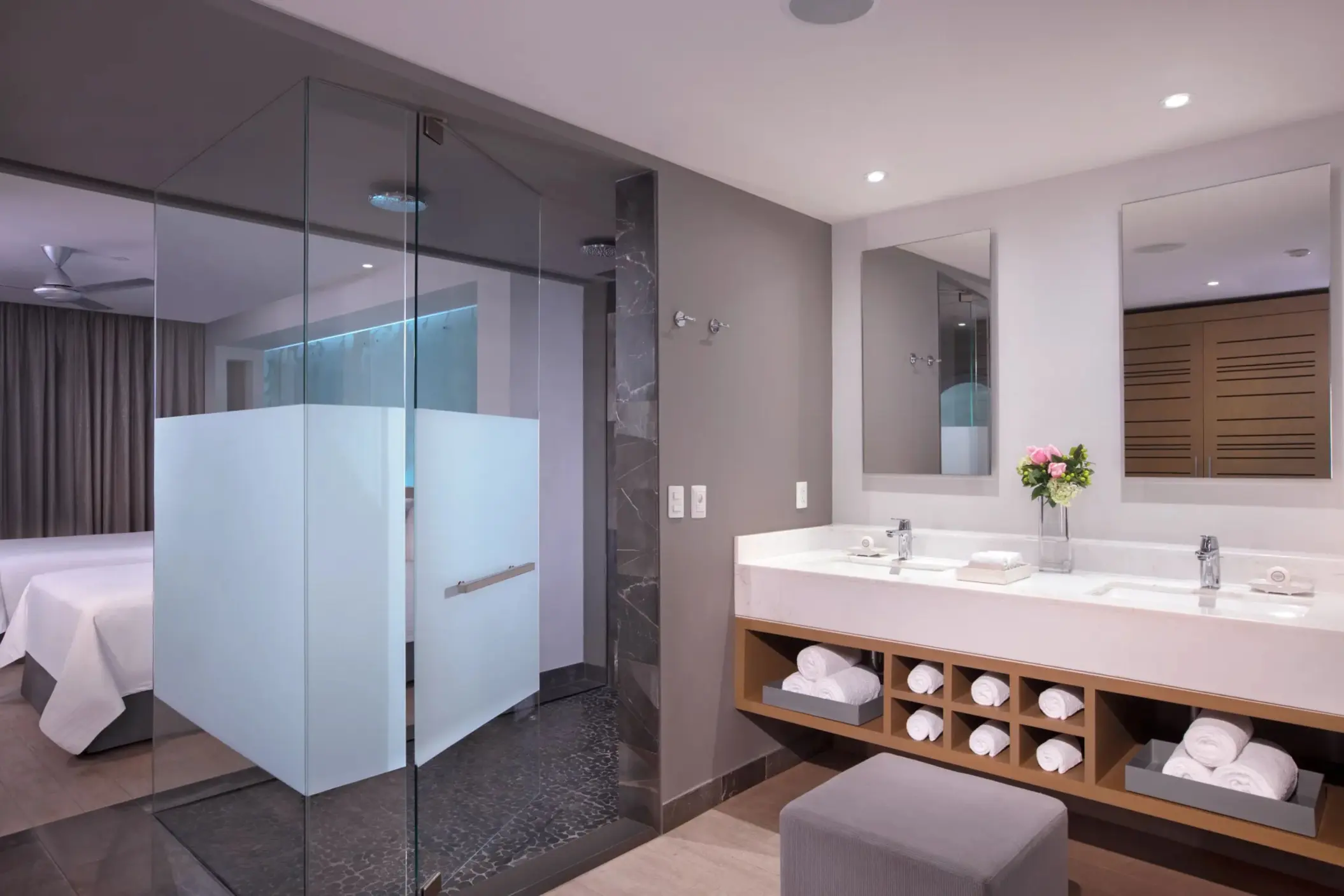 Modern junior suite bathroom with dual vanities, glass shower, and clean design.