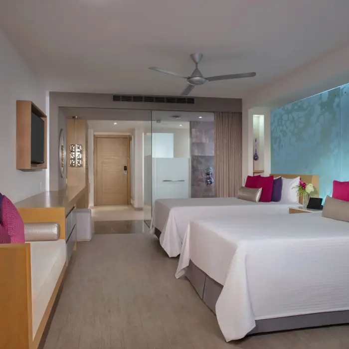 Spacious junior suite with two beds, soft lighting, and a relaxing modern vibe.