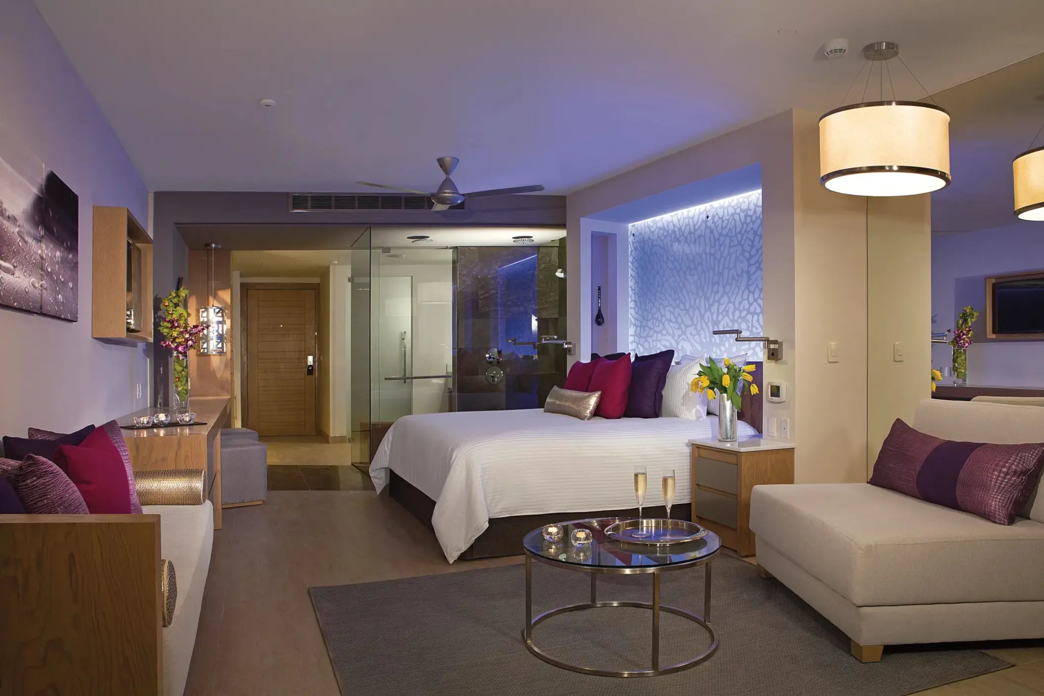 Spacious king suite at Breathless Riviera Cancun featuring mood lighting, a lounge area, and modern open-style bathroom.