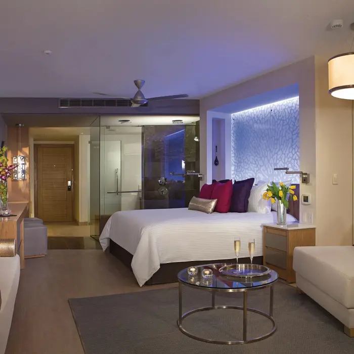 Spacious king suite at Breathless Riviera Cancun featuring mood lighting, a lounge area, and modern open-style bathroom.