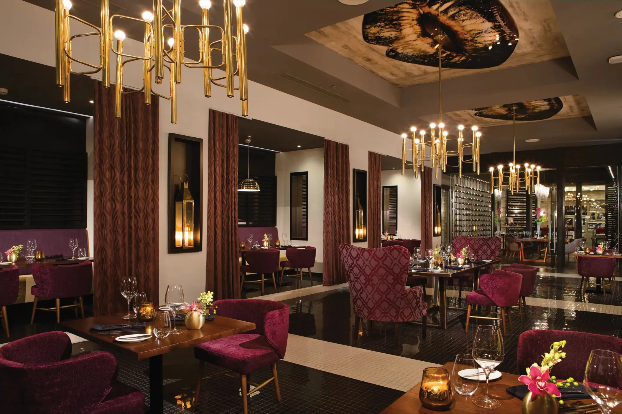 Elegant interior of Coquette restaurant featuring gold chandeliers and plush velvet seating.