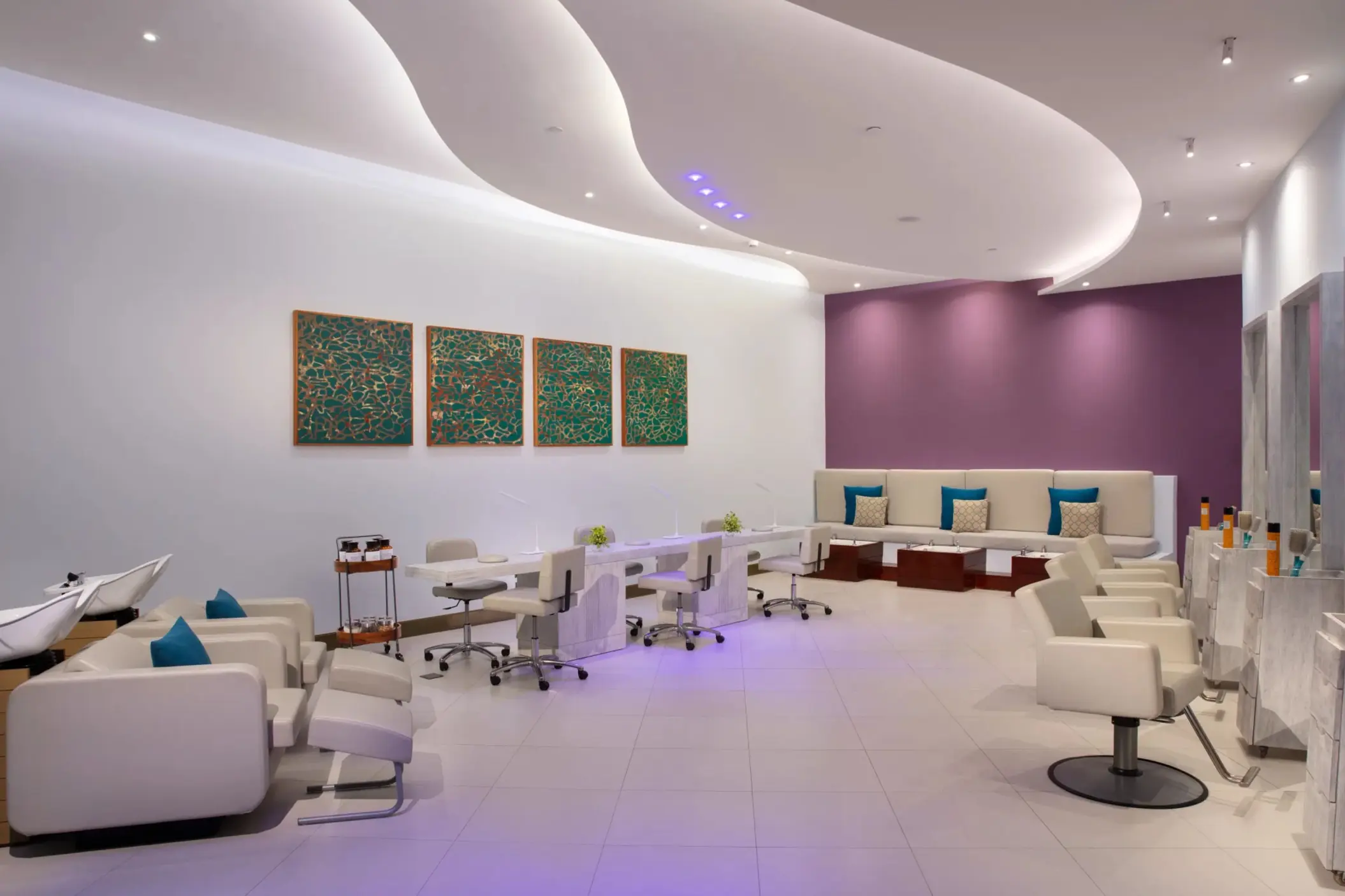 Salon area of the spa with manicure stations, wash chairs, and modern curved ceiling design.