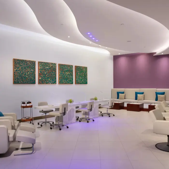 Salon area of the spa with manicure stations, wash chairs, and modern curved ceiling design.
