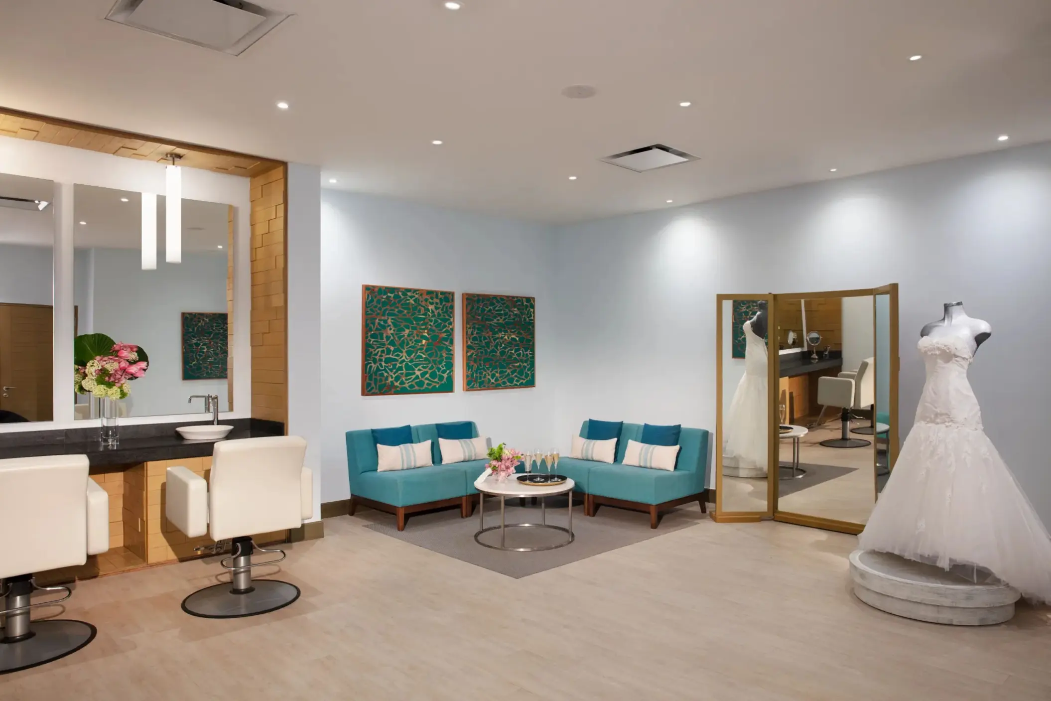 Bridal suite with mirrors, turquoise seating, and a mannequin in a wedding gown.