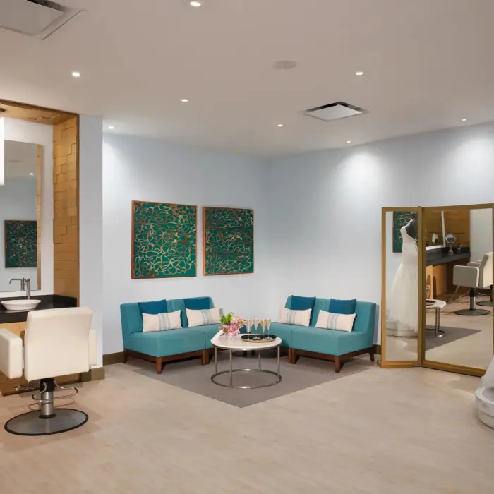Bridal suite with mirrors, turquoise seating, and a mannequin in a wedding gown.