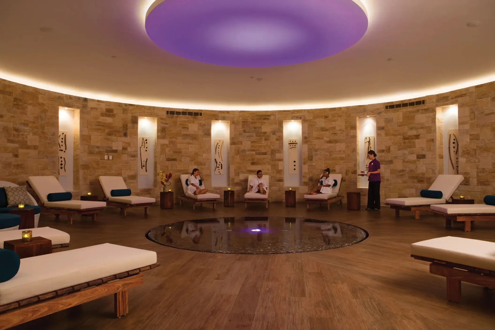Circular spa relaxation room with lounge chairs and tranquil lighting at Breathless Riviera Cancun.
