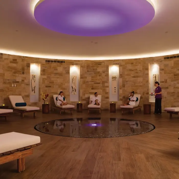 Circular spa relaxation room with lounge chairs and tranquil lighting at Breathless Riviera Cancun.