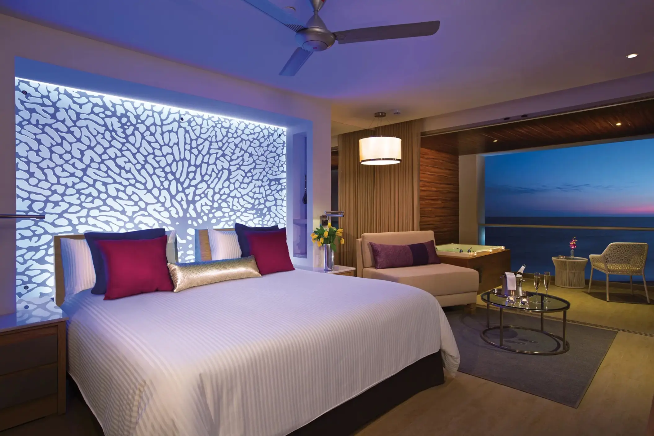 Oceanfront suite with illuminated headboard and twilight views.