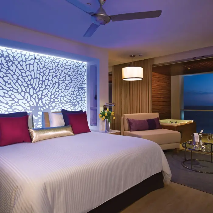 Oceanfront suite with illuminated headboard and twilight views.
