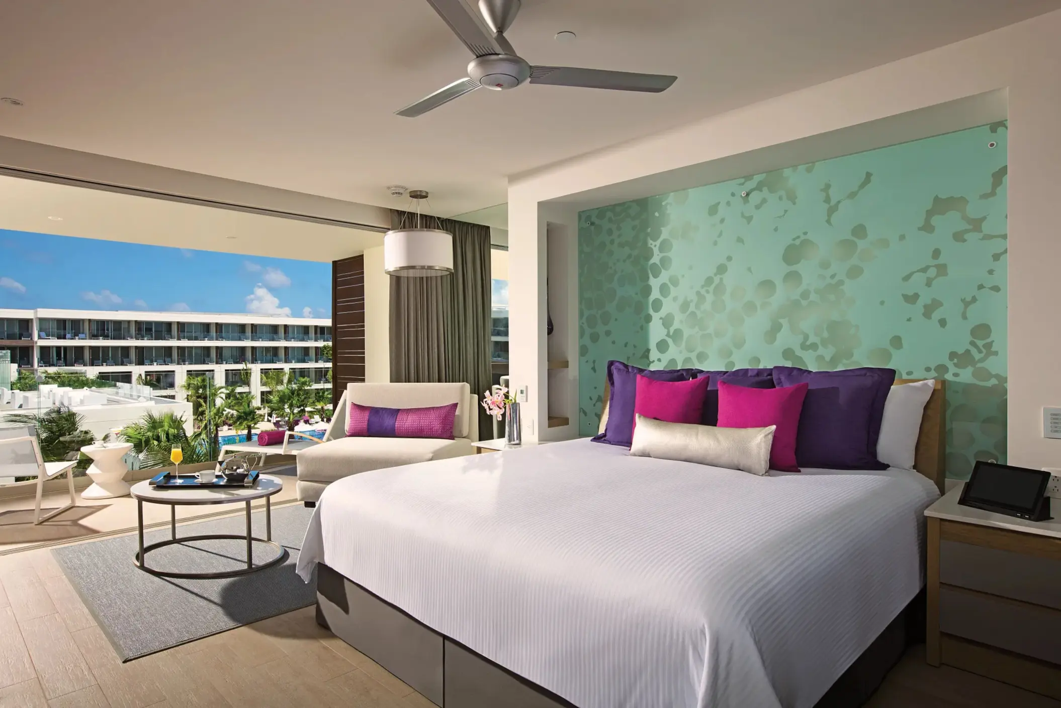 Spacious junior suite with ocean view balcony, king bed, and vibrant decor at Breathless Riviera Cancun.