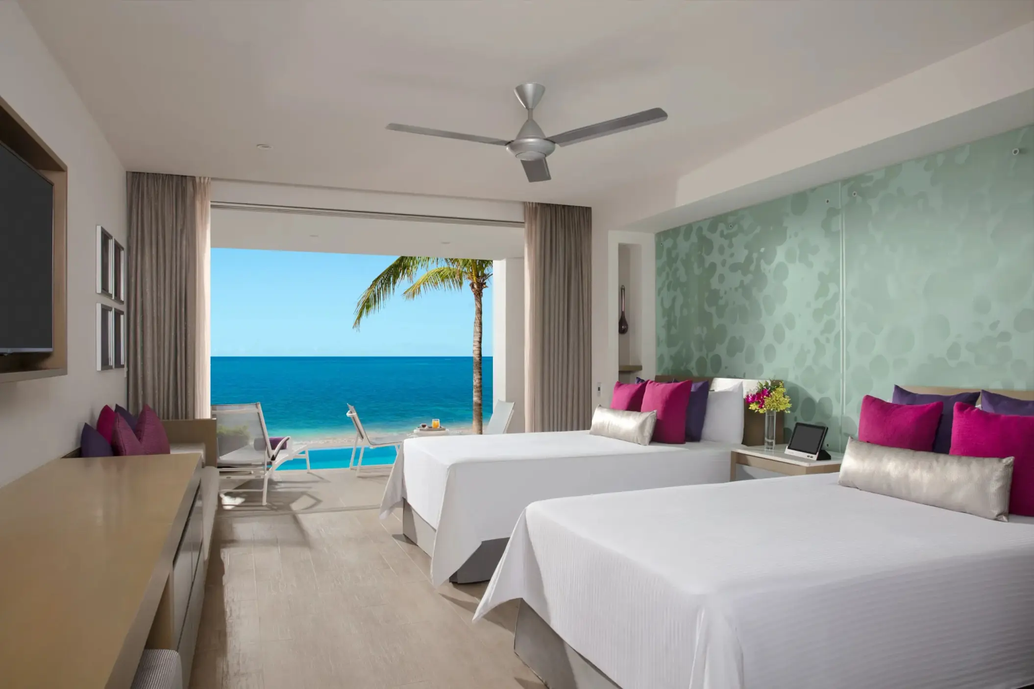 Junior suite with two double beds and oceanfront views, featuring private balcony and tropical design.
