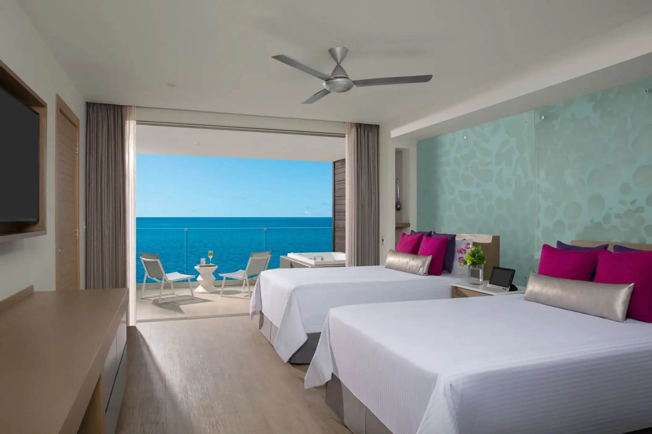 Oceanfront suite with two beds and private balcony featuring an outdoor whirlpool and sea views.
