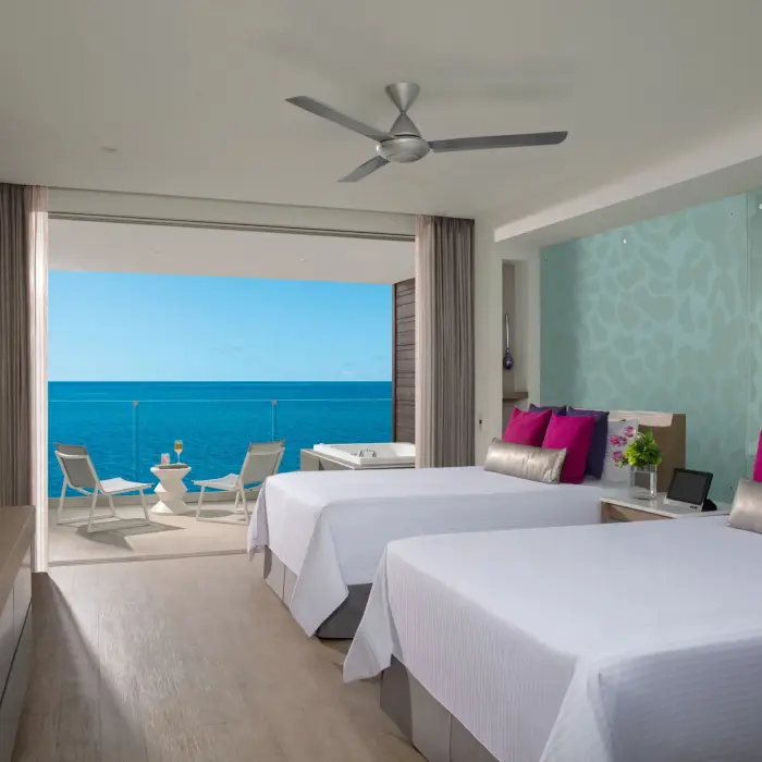 Oceanfront suite with two beds and private balcony featuring an outdoor whirlpool and sea views.