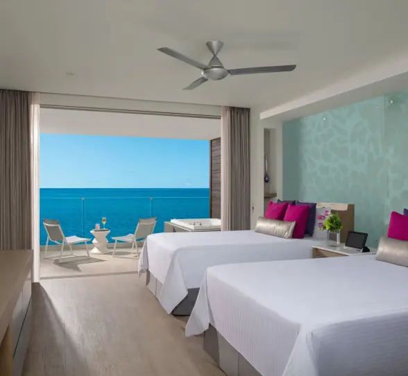 Oceanfront suite with two beds and private balcony featuring an outdoor whirlpool and sea views.