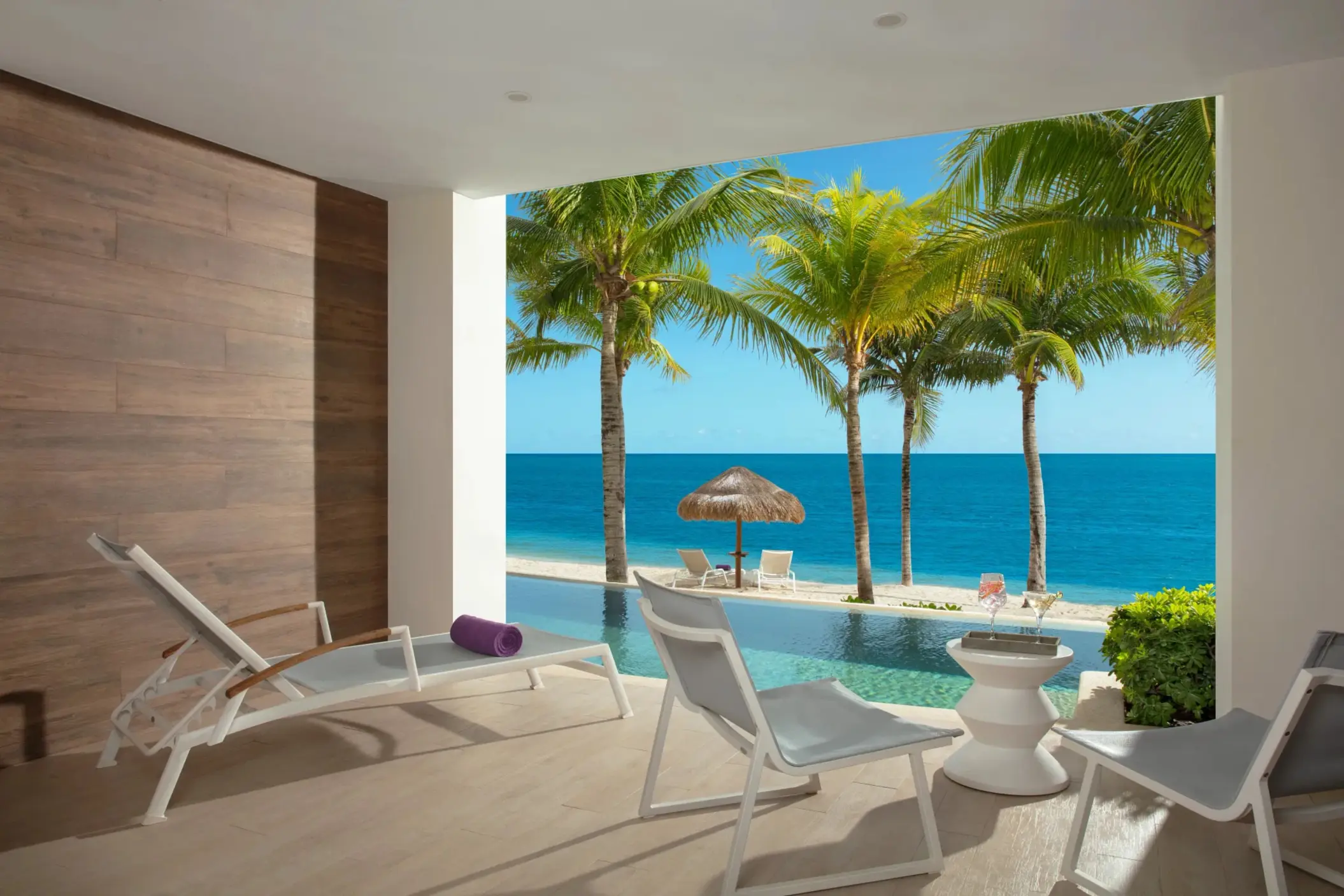 Private swim-up suite terrace with lounge chairs and palm-shaded ocean view.