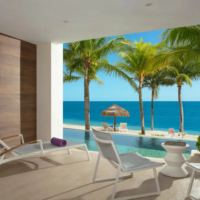 Private swim-up suite terrace with lounge chairs and palm-shaded ocean view.