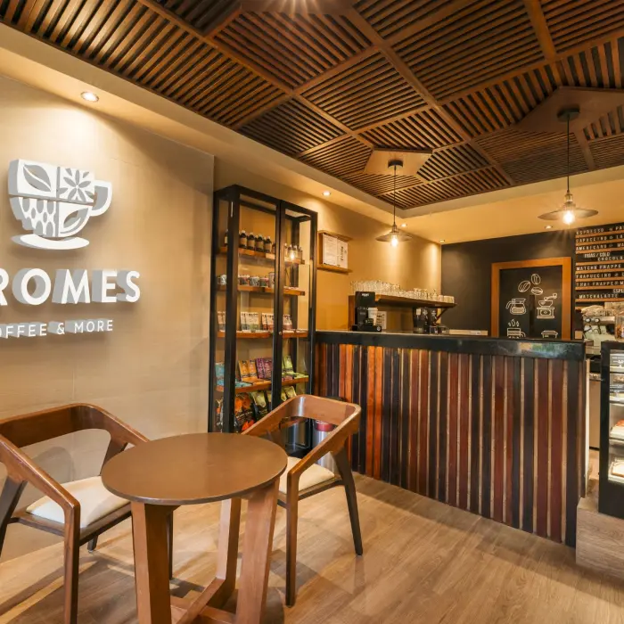 The inviting interior of Aromes Coffee & More cafe at Catalonia Playa Maroma, with warm lighting, wooden accents, and pastries on display.