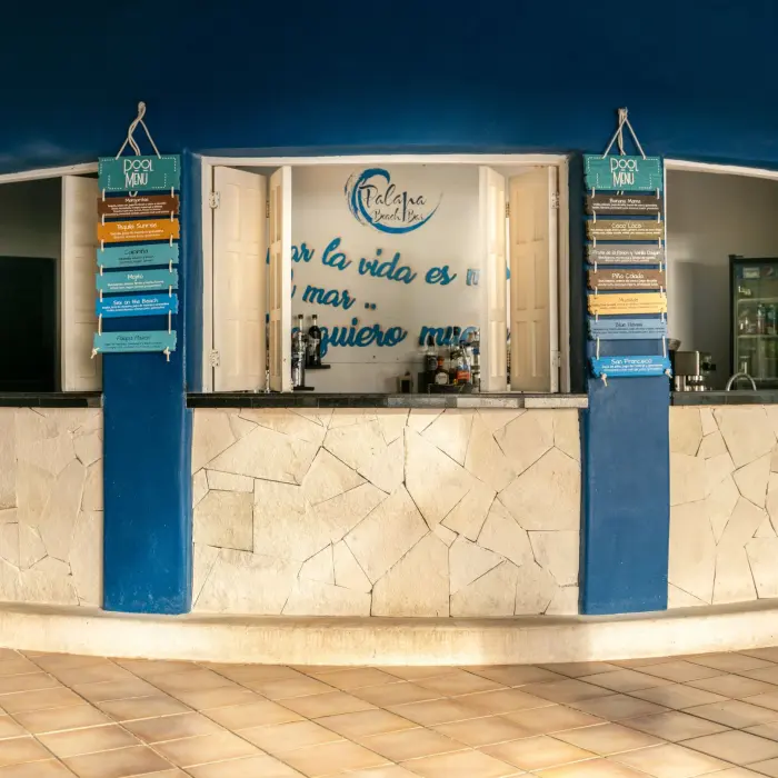 blue and white outdoor bar at Catalonia Playa Maroma with a curved counter and signs for Pool Menu, suggesting a refreshing spot.