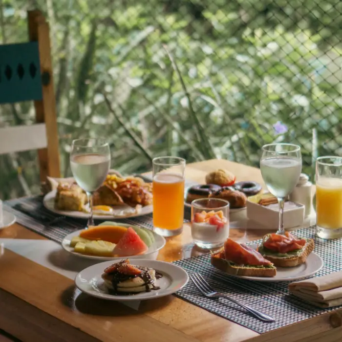 beautifully laid breakfast table at Catalonia Playa Maroma with fresh fruit, pastries, juices, and coffee, set outdoors amidst greenery.
