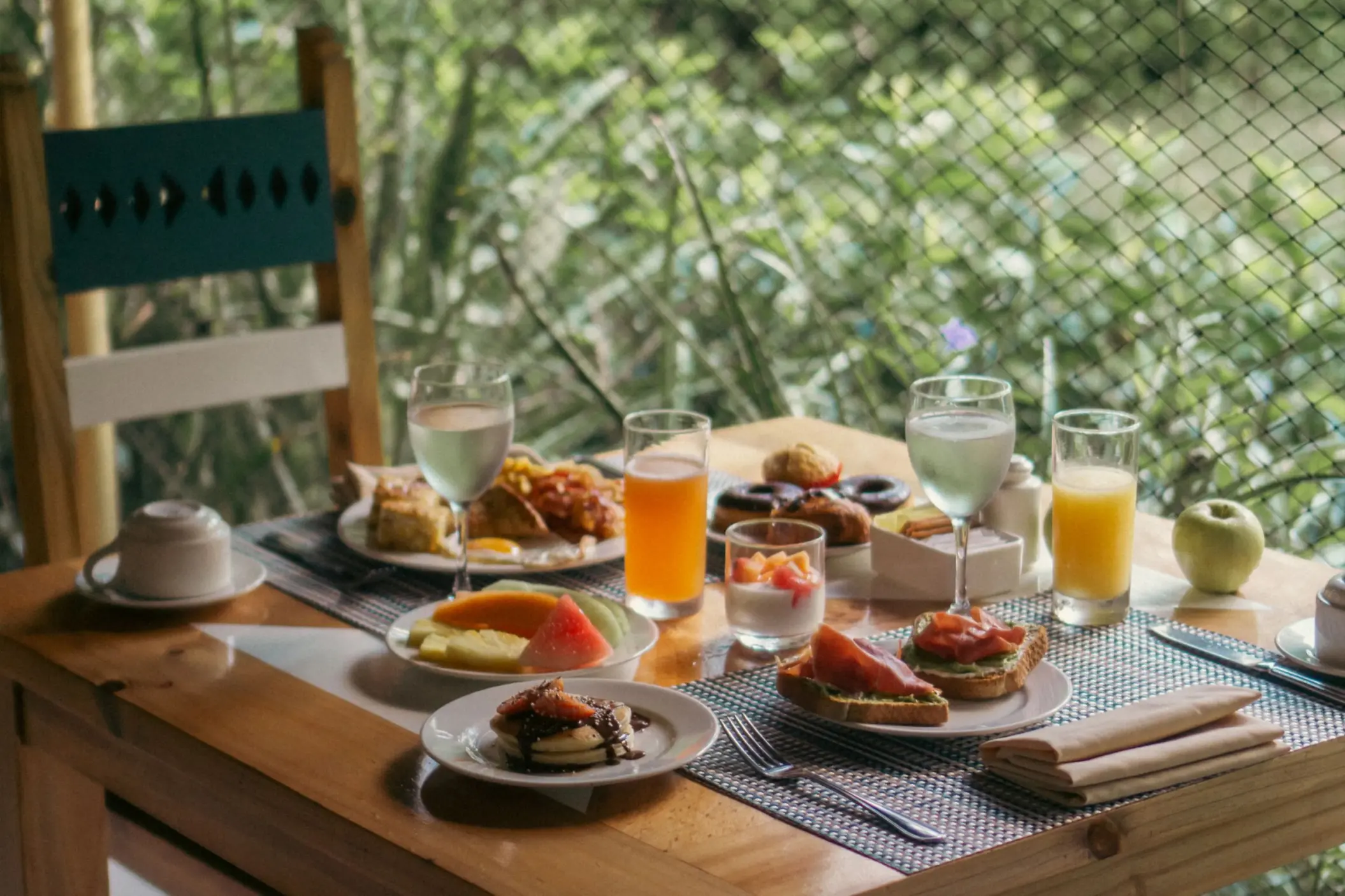 beautifully laid breakfast table at Catalonia Playa Maroma with fresh fruit, pastries, juices, and coffee, set outdoors amidst greenery.