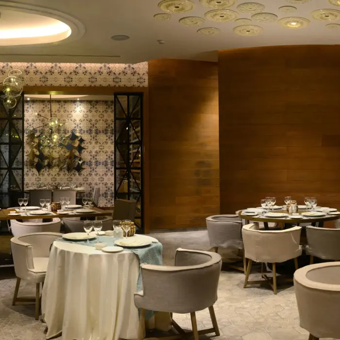A stylish restaurant interior at Catalonia Playa Maroma with elegantly set tables, patterned walls, and warm lighting.