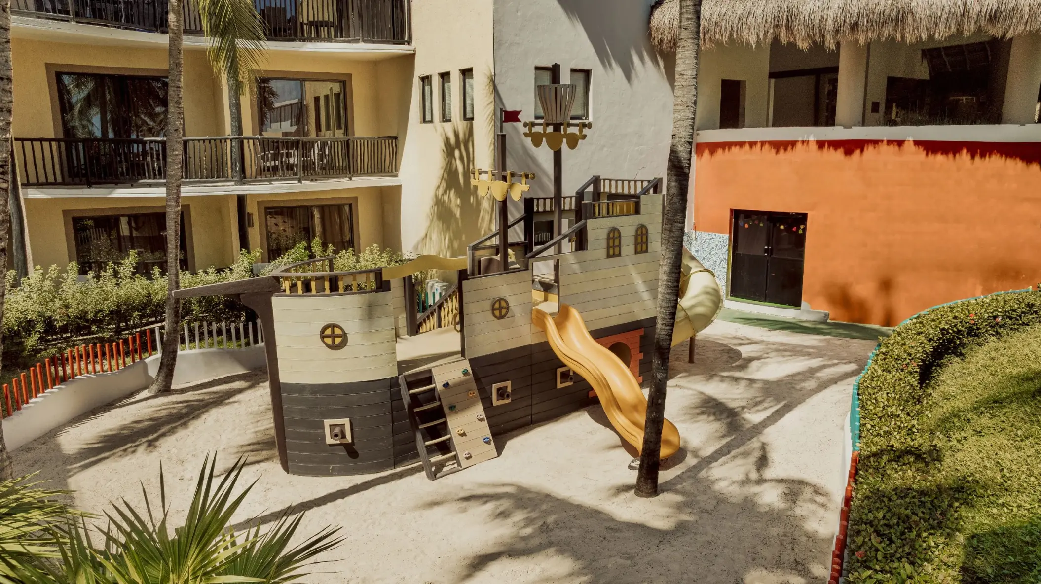 A sandy kids' play area featuring a pirate ship-themed playground with a slide.